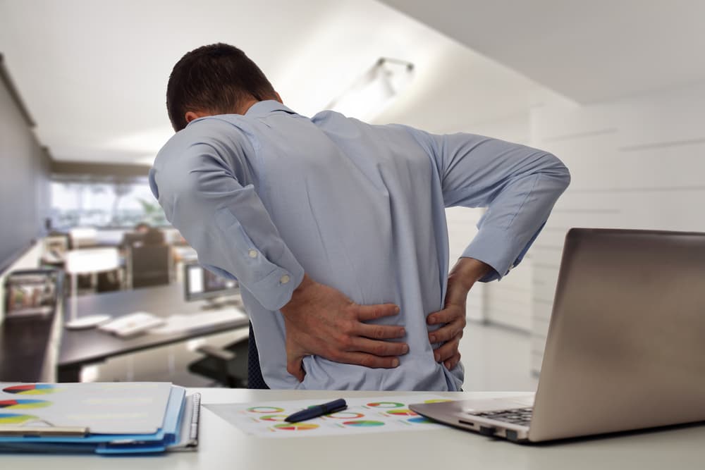 Business man with back pain an office . Pain relief concept