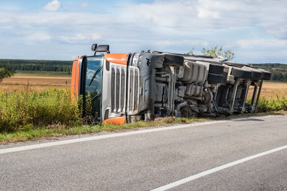 Overturned truck in field next to road