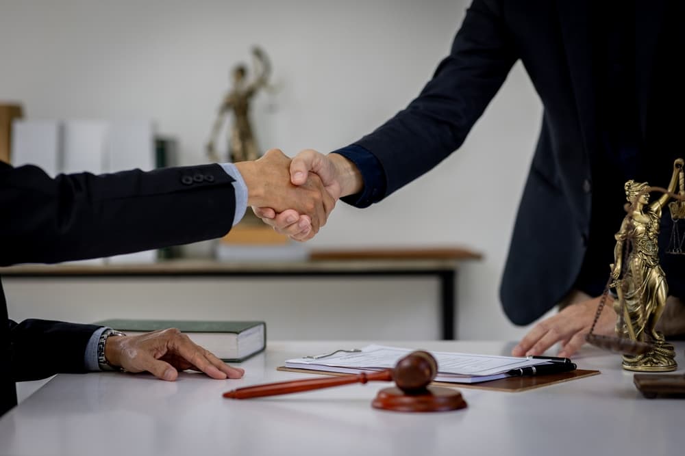 A lawyer and client shaking hands over legal documents, symbolizing justice and support in wrongful death cases.