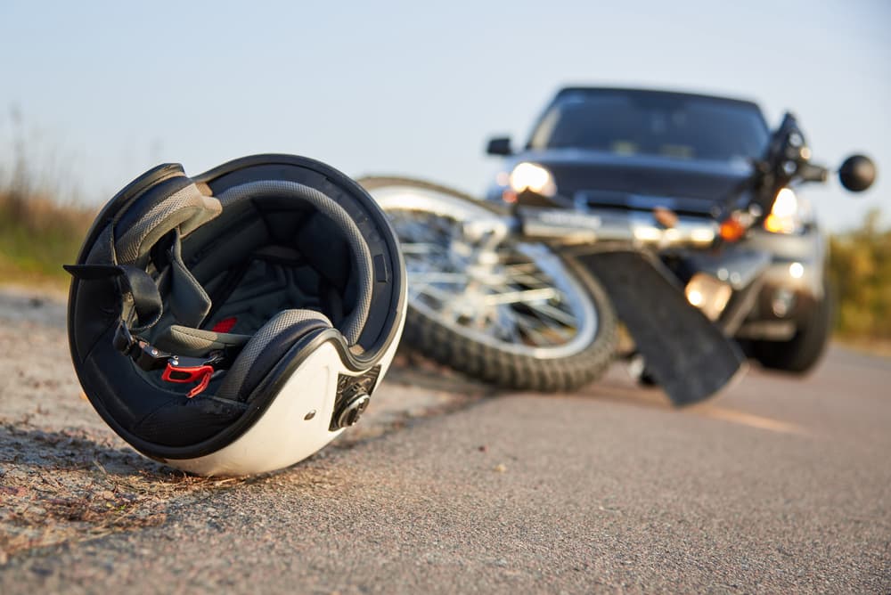 A crashed motorcycle, damaged car, and helmet highlight the need for a motorcycle accident lawyer's help.