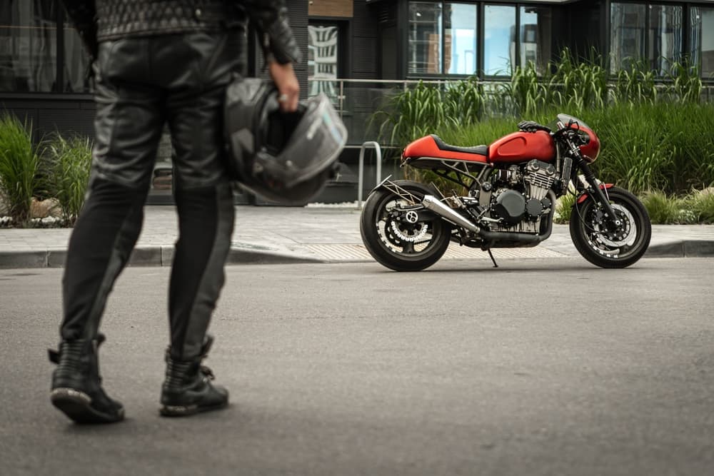 A motorcyclist approaches their bike, helmet in hand, prepared to ride safely and responsibly.