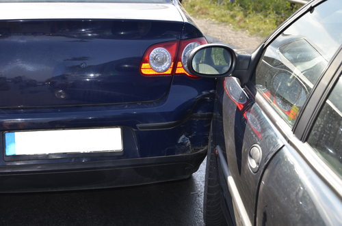 Two cars with overlapping damage from a sideswipe collision on the road.